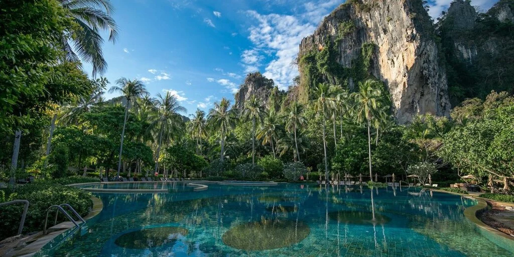 Big Hotel Pool, nestled in lush green palm tree garden, surrounded by cliffs