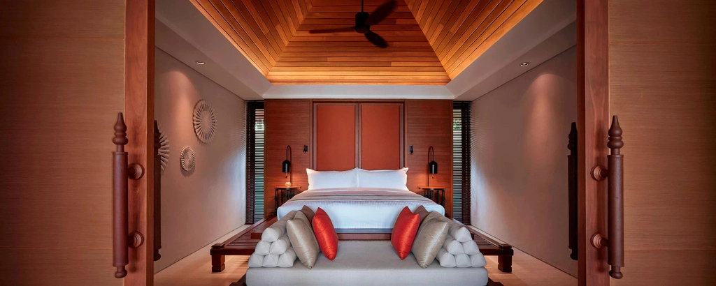 Hotel bedroom with wooden ceiling and traditional Thai interior.