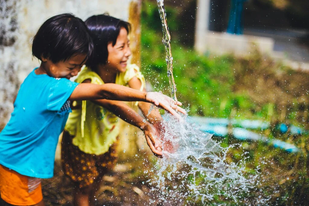 Two thai kids playing with water, vaccines for Thailand travel