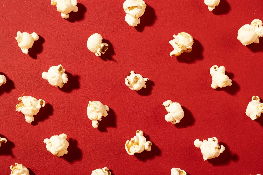 Popcorn on red background, best movies to watch on a plane