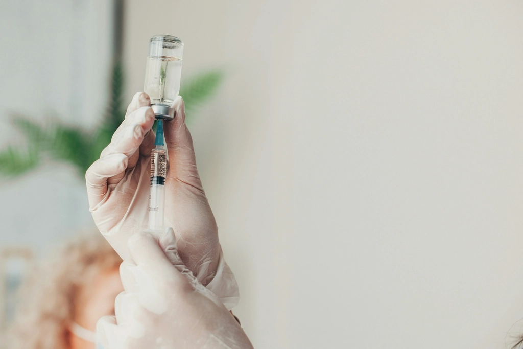 Hands holding a syringe, vaccines for Thailand travel.