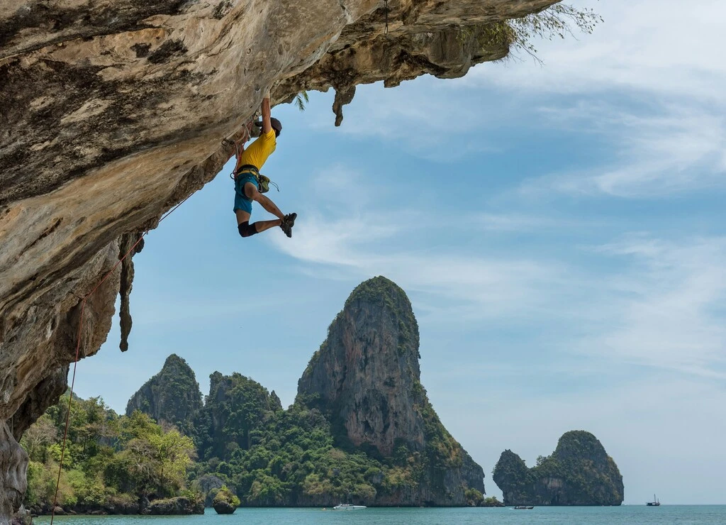 Rock climber with beautiful sea and hill surrounding in the background