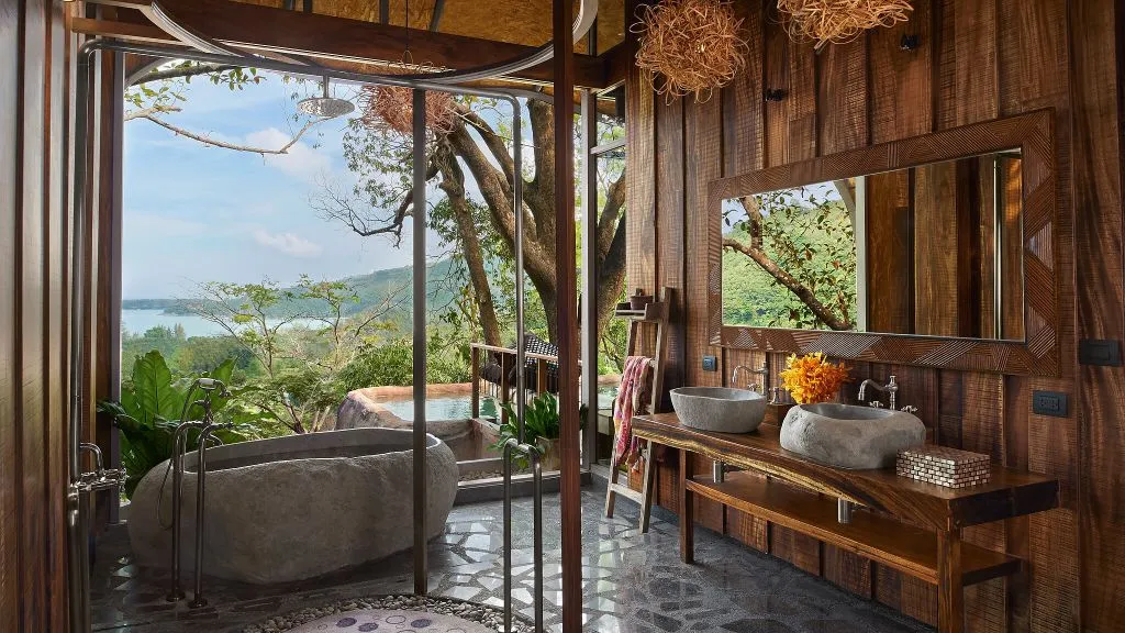 Wooden hotel bathroom with stone bathtub and breathtaking seaview. Best honeymoon resorts in Thailand