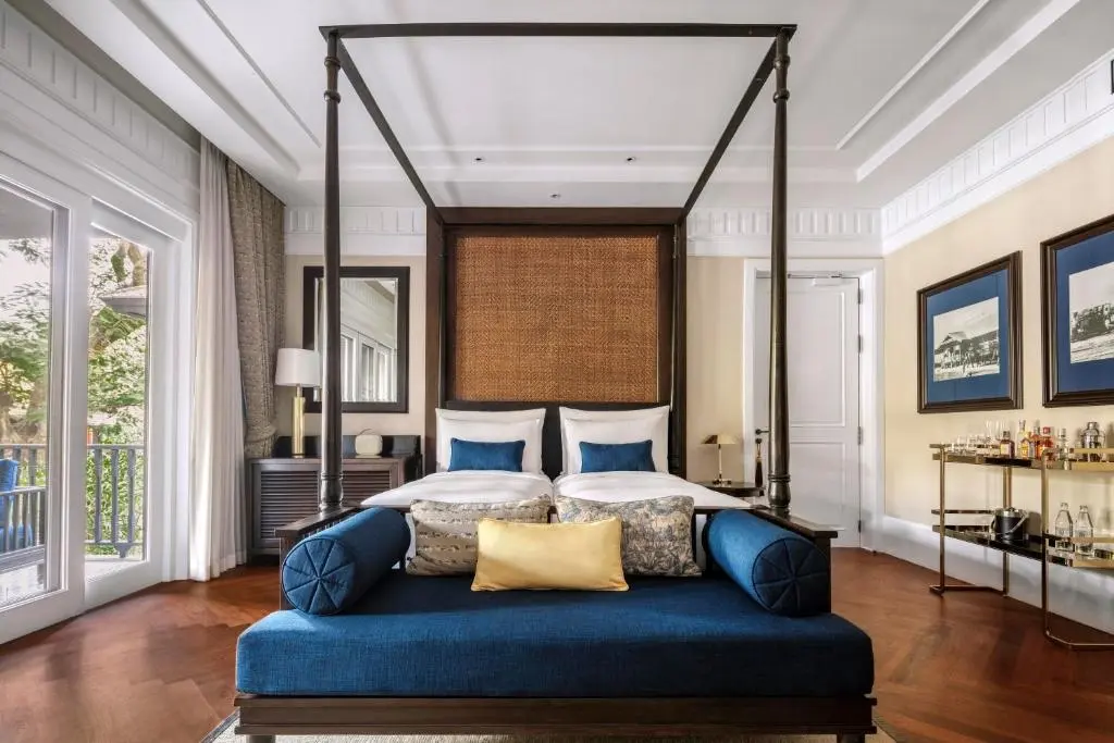 Hotelbedroom with king size bed, white colonial walls and a blue sofa.