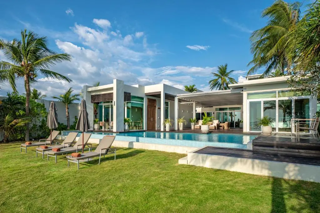 White villa with pool and green grass in front.