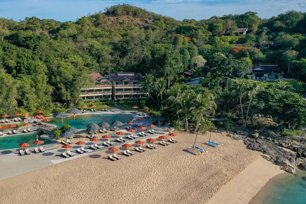 Birdsview of beach resort with pool and multiple sunbeds directly on the beach.