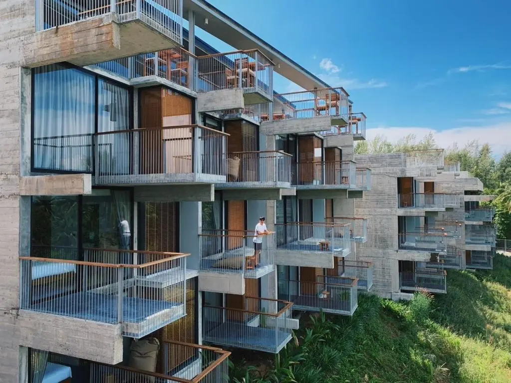 Concrete Hotel building with three stories in green surrounding.