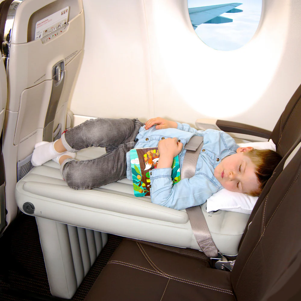 Young boy sleeping on inflatable airplane bed.