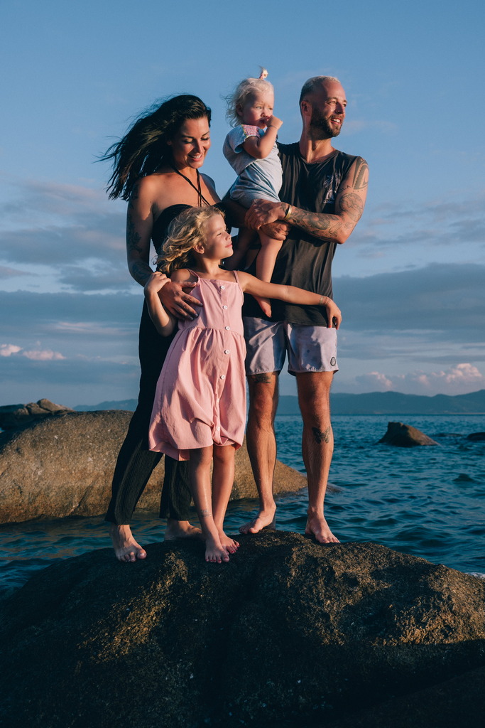 Family of four standing on a rock by the sea.
