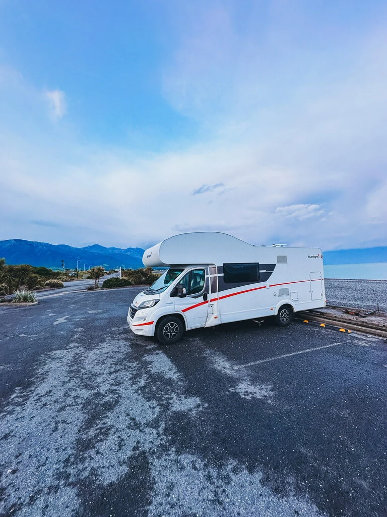 White Campervan standing on a parking lot on a shore.