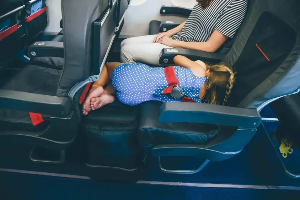 Girl laying on a plane seat with her legs on an inflatable airplane bed.