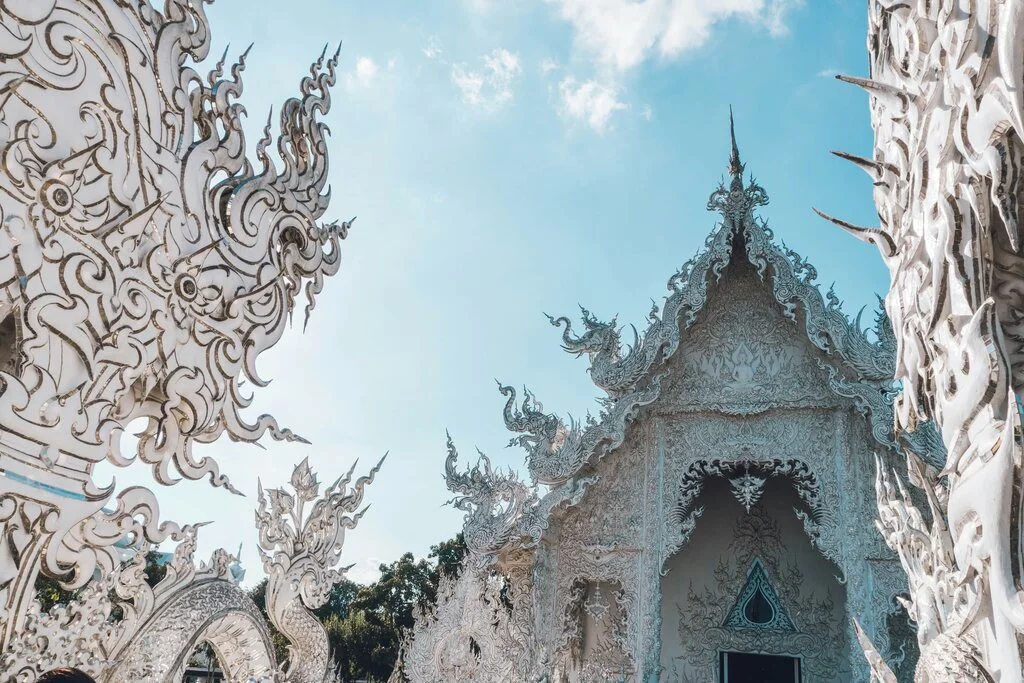 White temple building with pointed roofs and dragon embroidery.