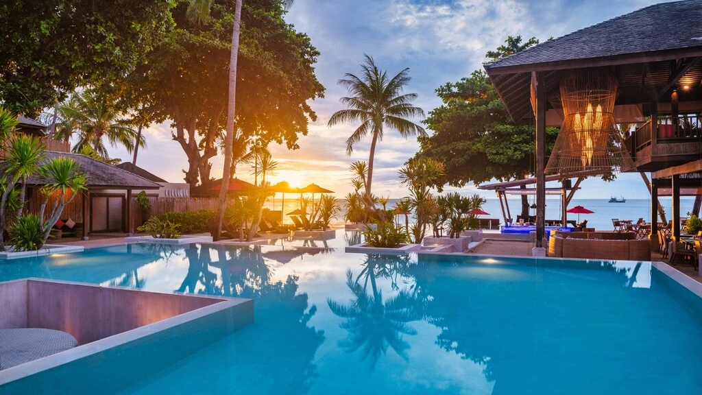 The 20 Best Honeymoon Resorts in Thailand: A Curated List 18 Huge Pool landscape in front of the sea, surrounded by trees and a wooden hotel terrasse.