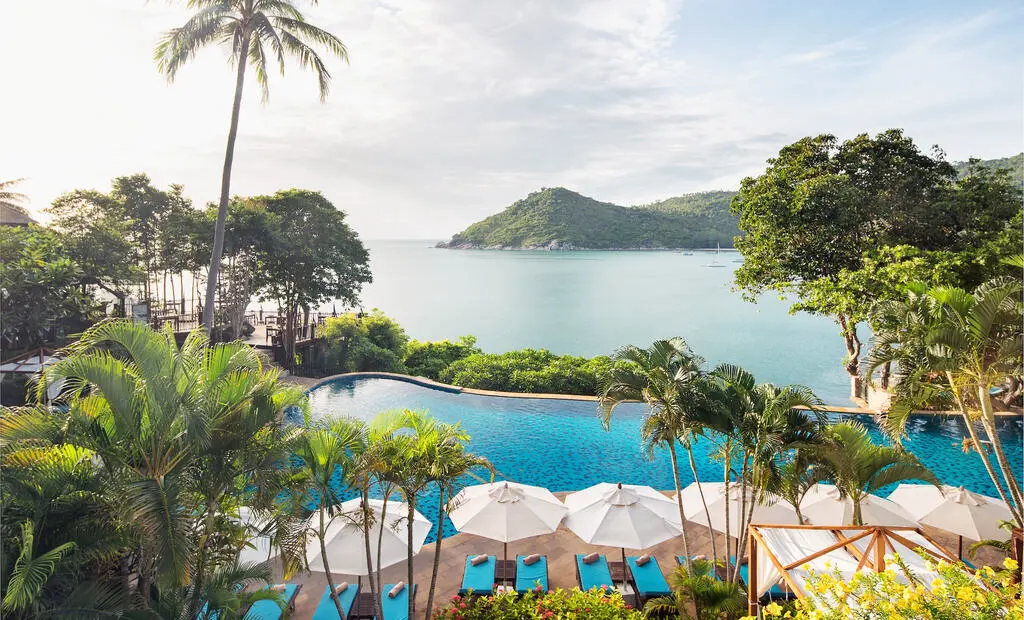 Hotel infinity pool with seaview, sun beds and lush jungle surrounding.