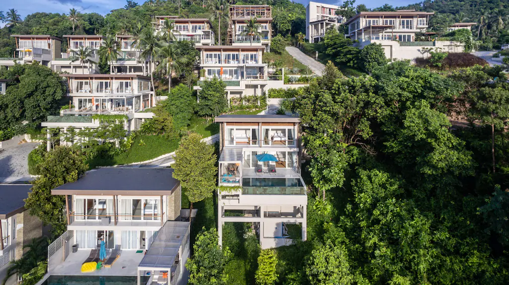 Green hill full of multi-storey white private pool villas.