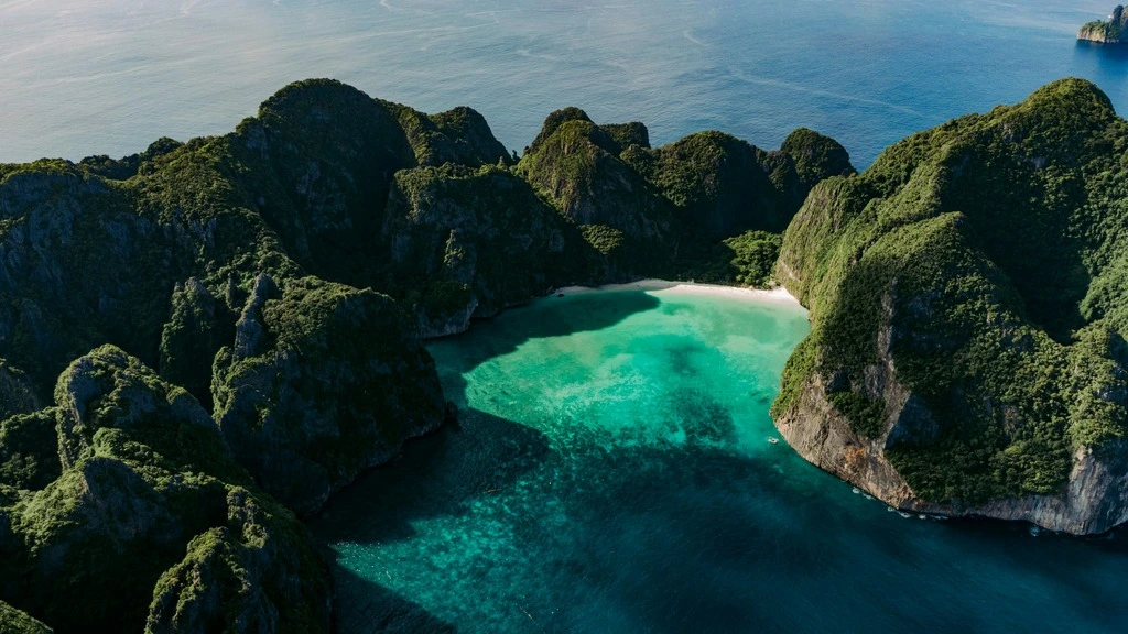 Birds view of secluded beach in hilly island landscape.