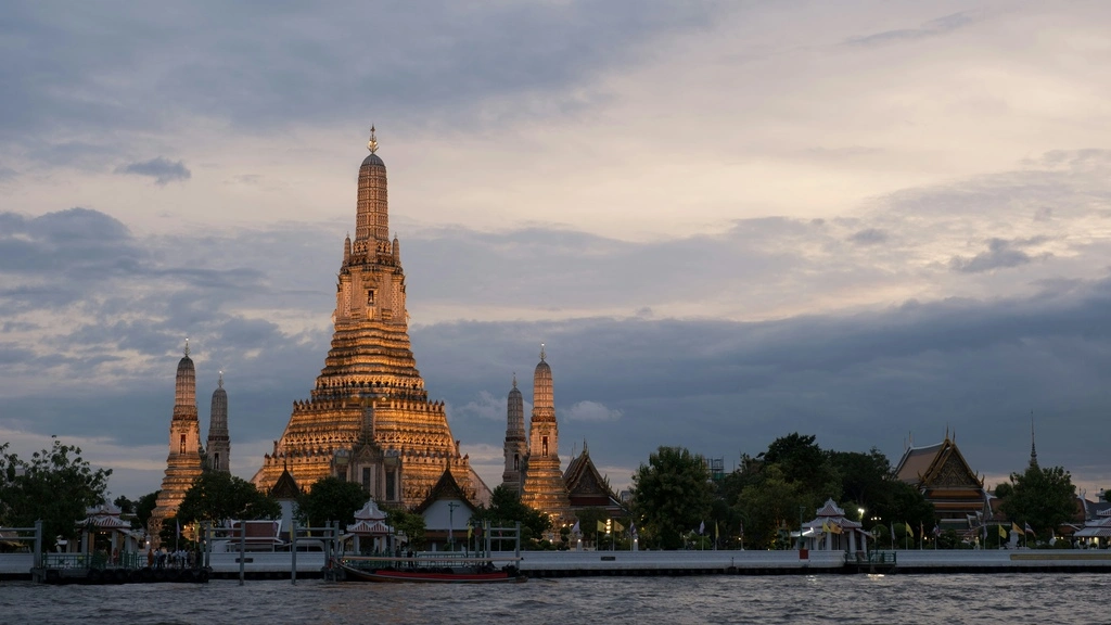 Large golden temple tower by a river at dawn.