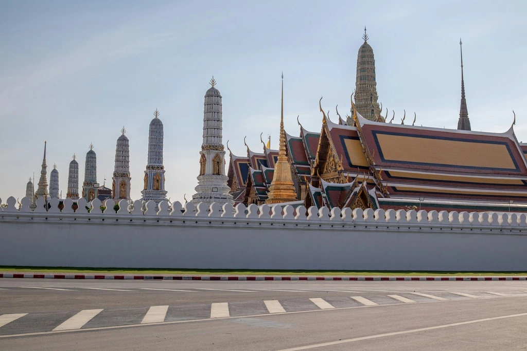 Big temple and palace complex behind a white wall on a big street.