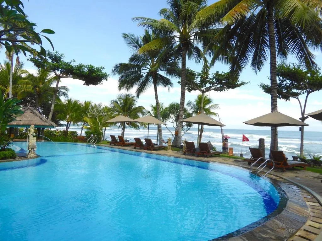 A pool with umbrellas and chairs by the beach.