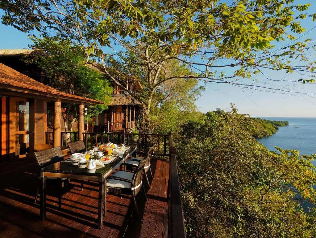 A table with food on it outside of a house with sea view.