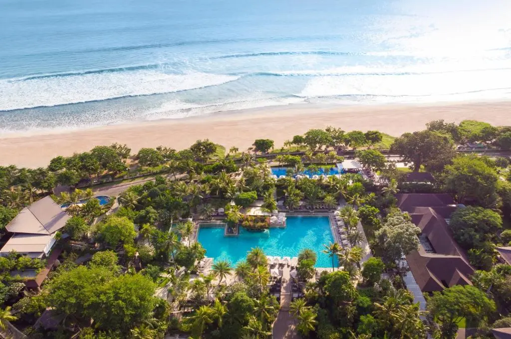 A swimming pool surrounded by trees and a beach.