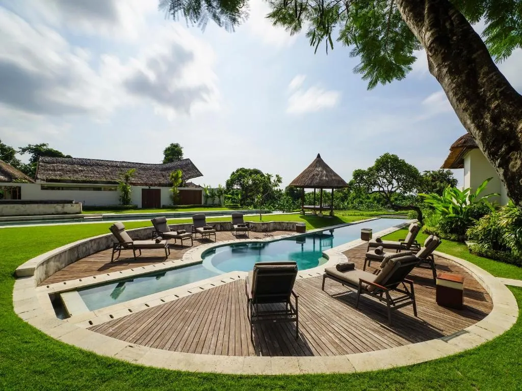 A pool with chairs and a tree in the back.