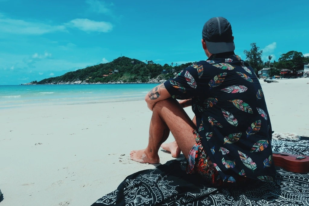 Guide to the Best Koh Phangan Beaches in 2025 4 A man sitting on a beach looking at the water.