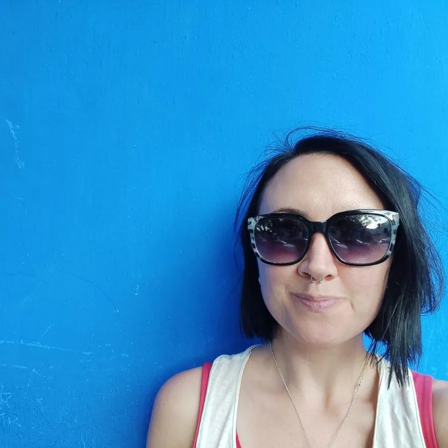 A woman wearing sunglasses and smiling.