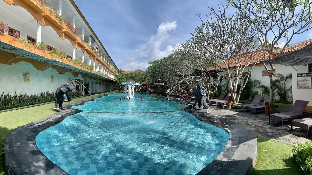 A pool with statues and trees around it.