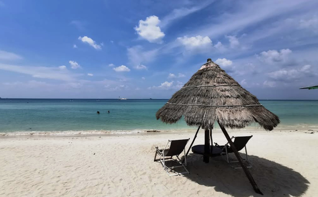 Tropical beach with bamboo umbrella.