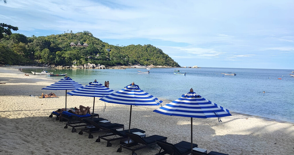 Beach with striped sun umbrellas.