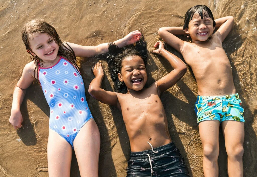 A group of children lying on the sand.