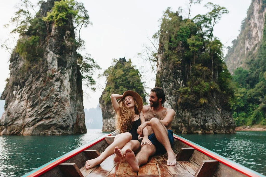 A man and woman in a longtail boat in Thailand. How much is a trip to Thailand?