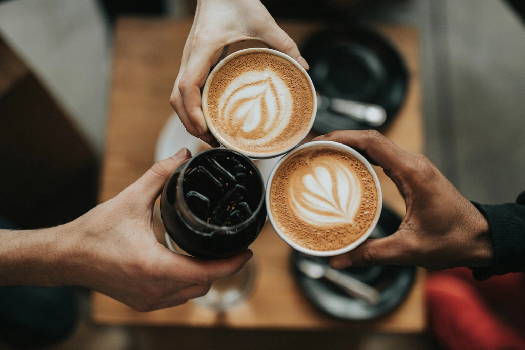 A group of three hands holding cups of coffee.