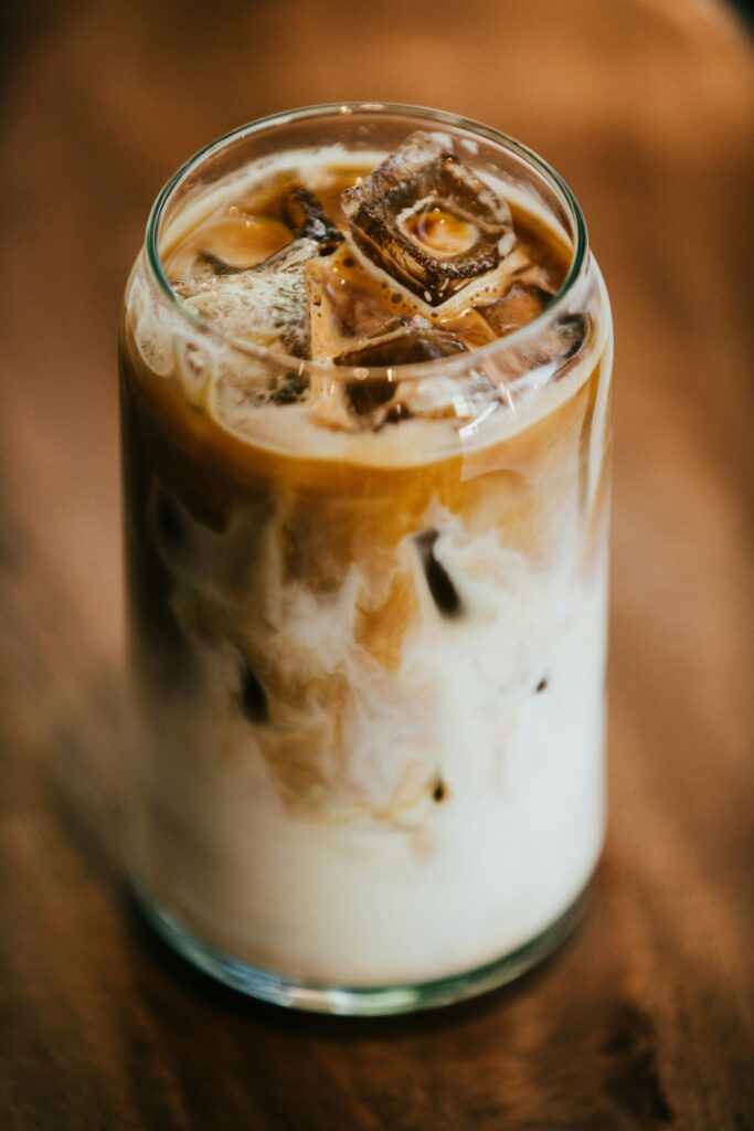 A glass of coffee latte on a wooden table.
