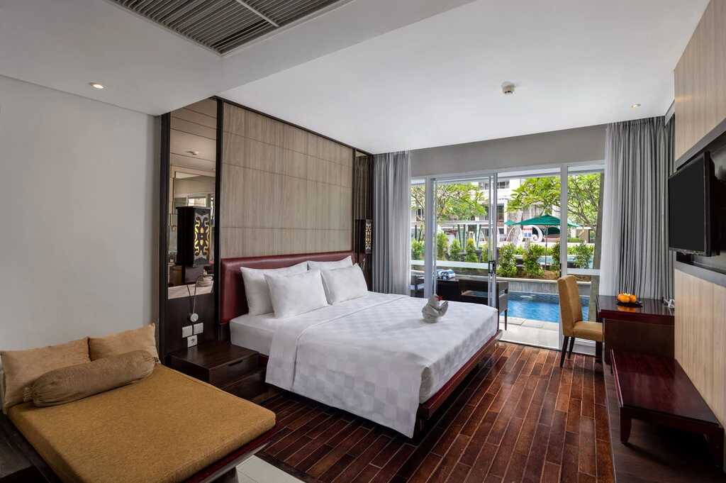 A hotel room with a bed and a pool in the background.