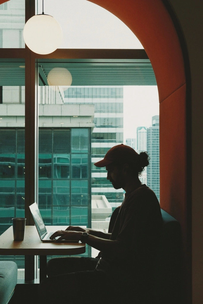 A man sitting at a table with a laptop. Expat Jobs in Thailand.