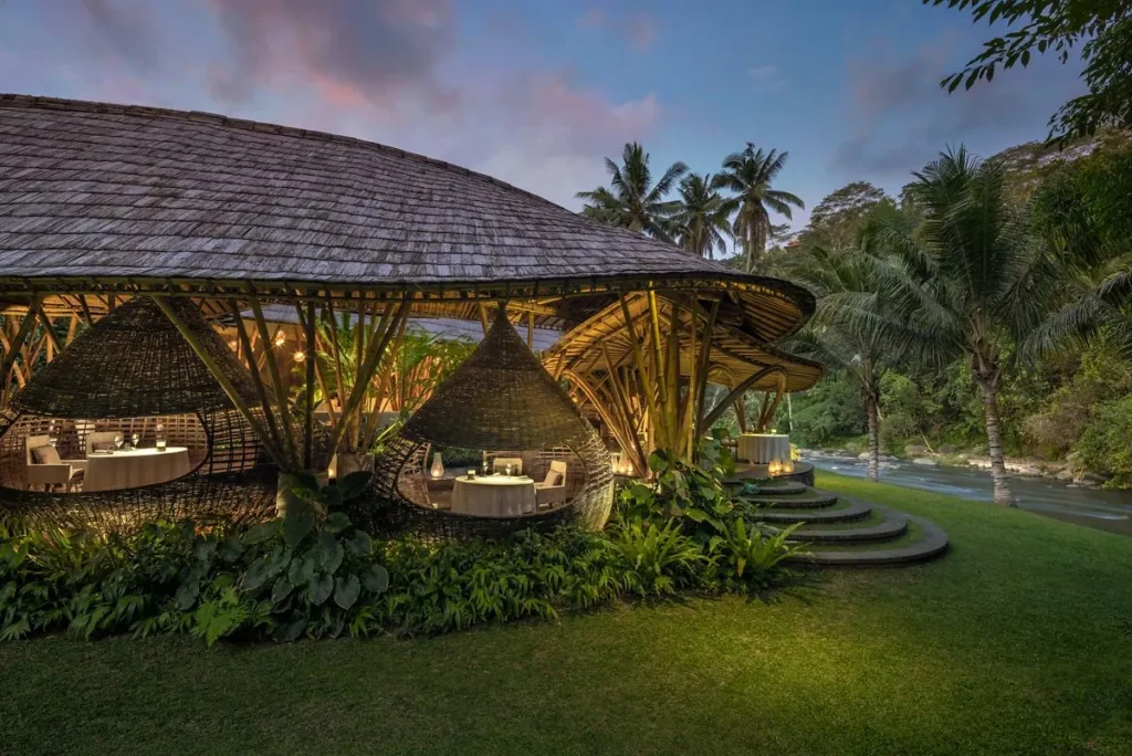 A gazebo with a round table and chairs in front of a river.