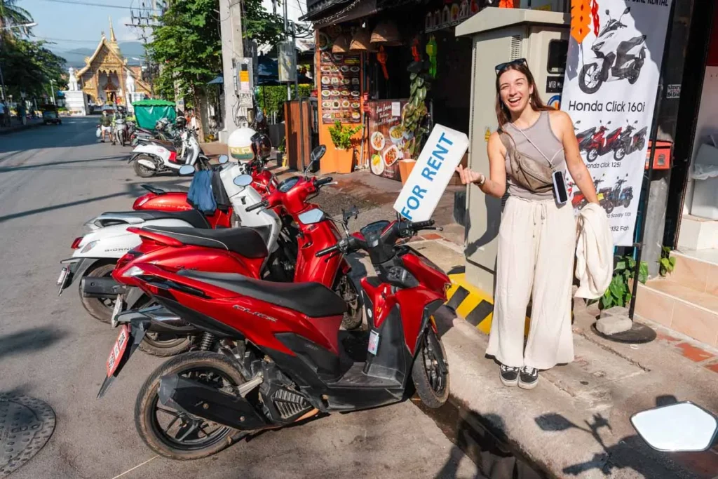 Ultimate 3-Day Chiang Mai Itinerary for First Timers 13 A woman holding a sign next to a red scooter.