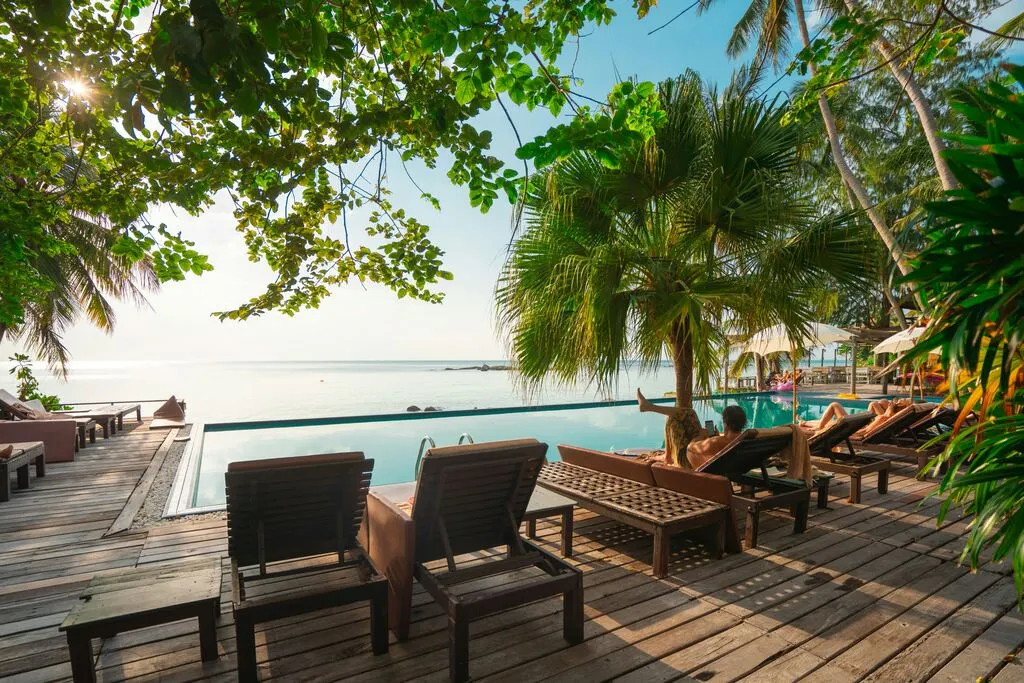 Guide to the Best Koh Phangan Beaches in 2025 2 A group of people sitting on a wooden deck by a pool.