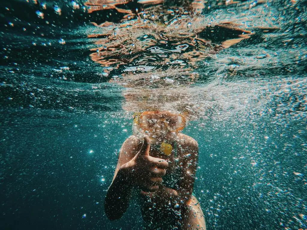 A person swimming underwater with bubbles. Best Snorkeling Spots in Thailand.