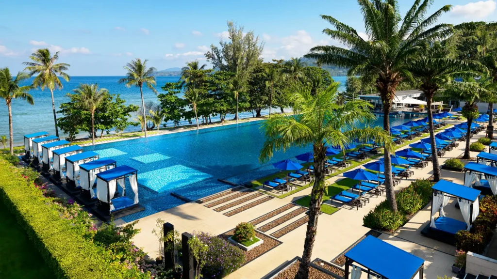 Hyatt Regency Phuket with Kids – My Honest Review 3 A large pool with chairs and umbrellas by the water.