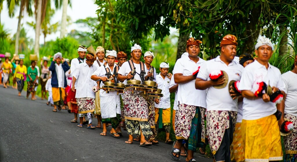 Bali Family Guide – Top 8 Things to do in Ubud with Kids 1 A group of Balinese people in traditional clothing walking on a street.