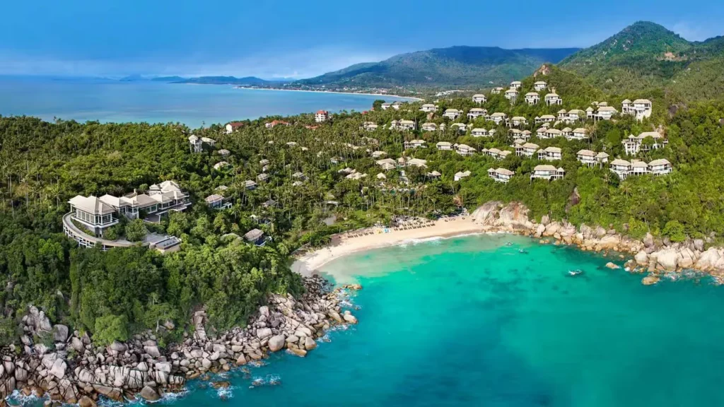 An aerial shot of a beach with houses and trees.