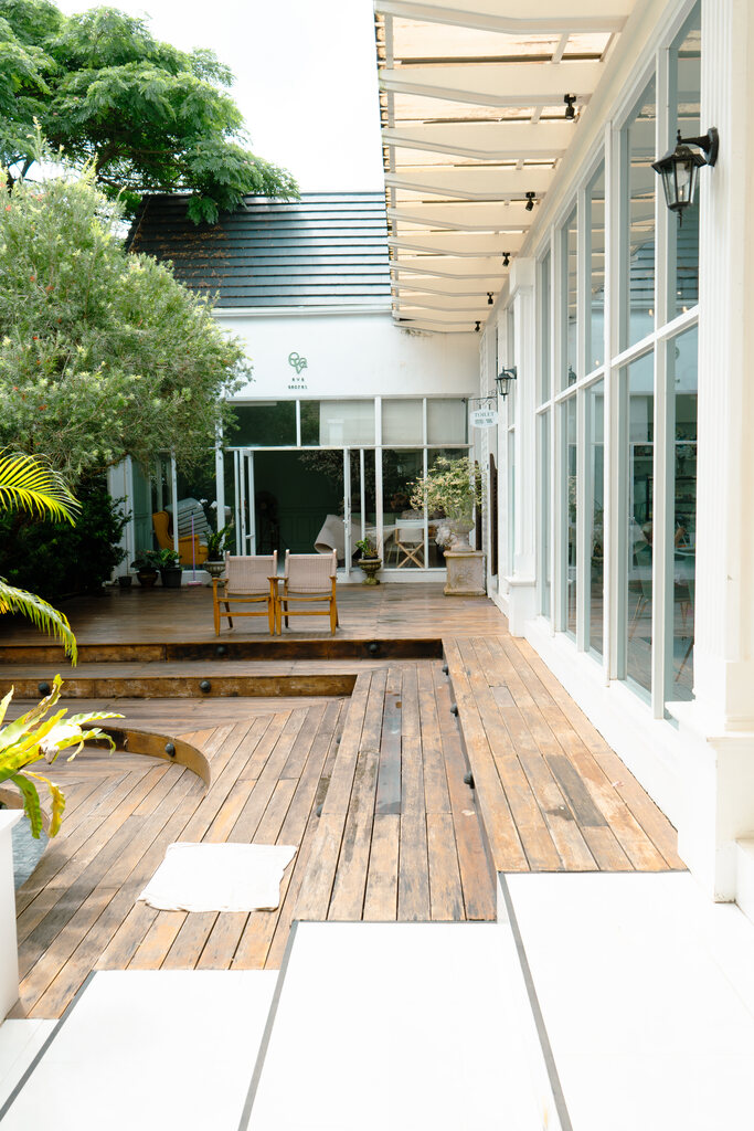 Eva Cafe Koh Samui: Cutest Family Cafe on the Island? 11 A patio with a wood deck and a wood patio with a tree and plants.