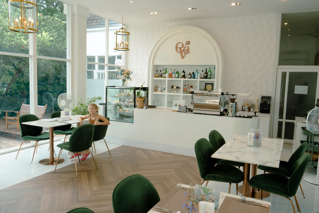 Eva Cafe Koh Samui: Cutest Family Cafe on the Island? 6 A girl sitting at a table in a room with green chairs.