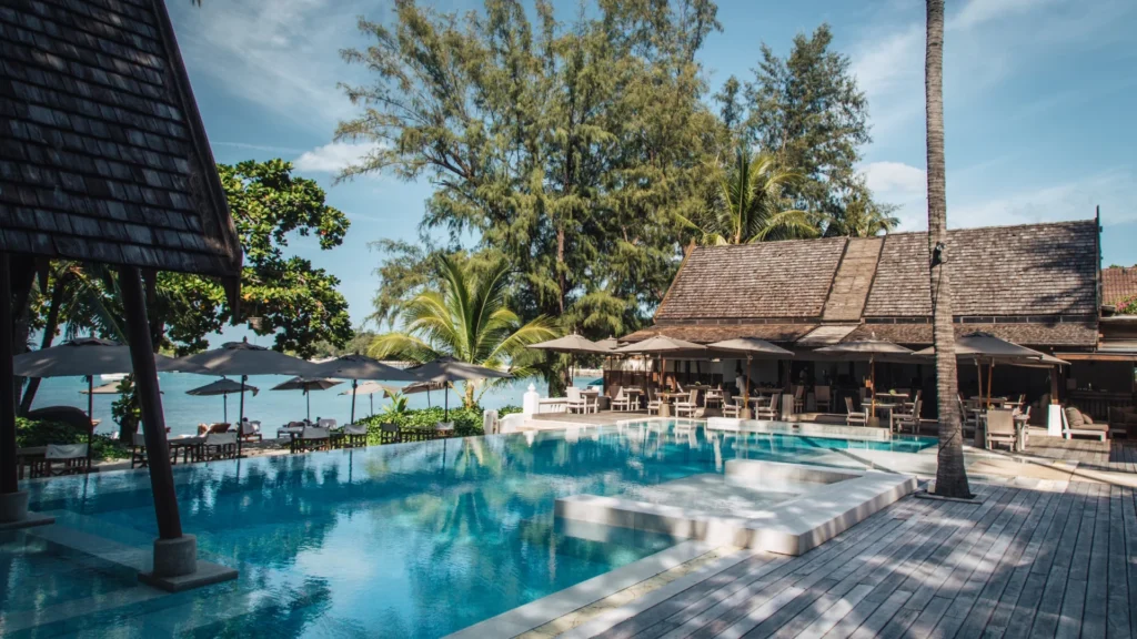 A swimming pool with a building and umbrellas.