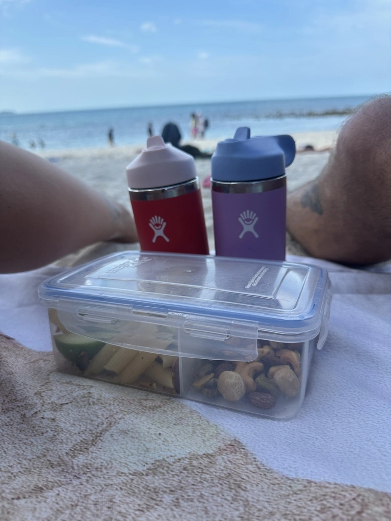 31 Healthy Travel Snacks for Kids (100% Veggie) 2 A person's leg and a container with food on a towel.