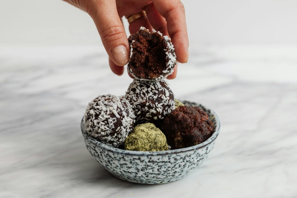 31 Healthy Travel Snacks for Kids (100% Veggie) 14 A hand holding a round chocolate ball in a bowl.