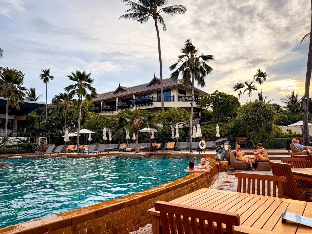 Anantara Bophut Koh Samui – Honest Family Review 2025 19 A pool with people sitting on chairs and palm trees.